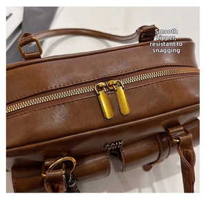 Detailed top view of the vintage brown tote bag featuring smooth double golden zippers