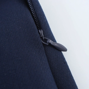 Detailed macro view of dark blue fabric featuring a precise invisible zipper and puller