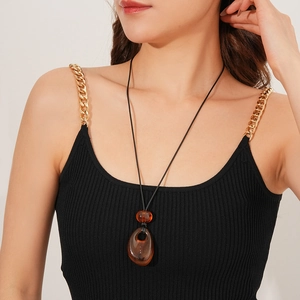 Detailed view of amber teardrop pendant with black wax cord on a female model