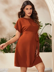 Detail of the rust red maternity dress featuring a waist-tie design and crew neck style
