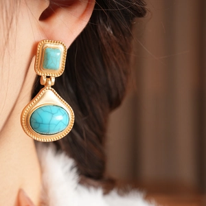 Detail view of vintage gold resin earrings with turquoise stones on model's ear