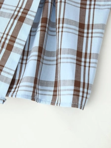 Macro view of light blue and brown plaid poplin fabric detail with single-needle hem finish