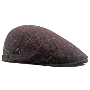 Detail of dark brown herringbone tweed flat cap with adjustable bronze metal buckle