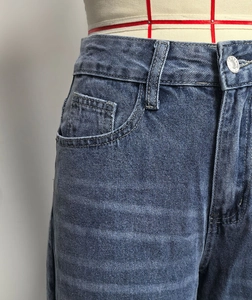 Close-up of high-waist detail on dark blue washed vintage jeans with metal button