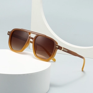 Retro pilot sunglasses with amber gradient frame and brown lenses on a white display pedestal