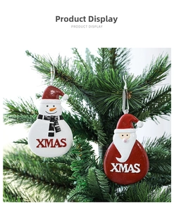 Detail of resin XMAS ornaments featuring Santa and Snowman hanging on a green tree branch