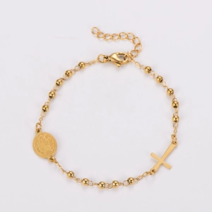 Macro view of gold beaded chain bracelet with religious cross and medallion charms