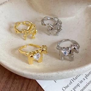 Detail of gold and silver Pegasus rings with heart zircon in a vintage ceramic tray