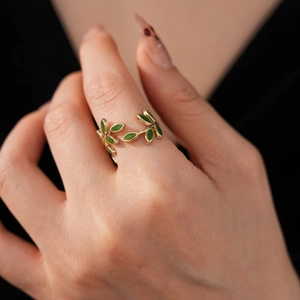 Macro detail of golden leaf ring with green enamel inlay on a hand for fashion styling