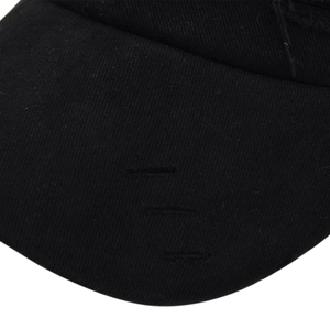 Close-up of black distressed cotton baseball cap showing ripped details and twill texture