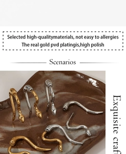 Close-up of gold and silver snake-shaped 316L stainless steel earrings on a tray