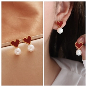Elegant heart-shaped red enamel pearl earrings with gold trim on gold silk background