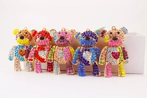 Close-up of five colorful crystal-encrusted metal bear charms with heart patterns