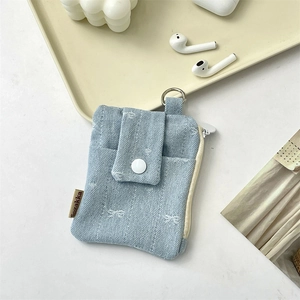 Detail of blue denim card holder with white snap button and silver metal D-ring hook