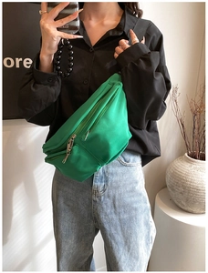 Detail of green nylon crossbody bag with adjustable strap shown on model in mirror