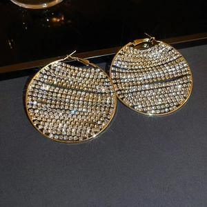 Macro shot of large gold-tone hoop earrings with sparkling rhinestones and starburst effects
