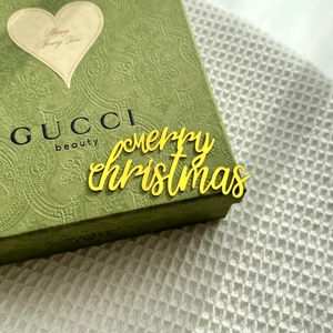 Macro detail of yellow acrylic Merry Christmas cake topper on luxury gift packaging