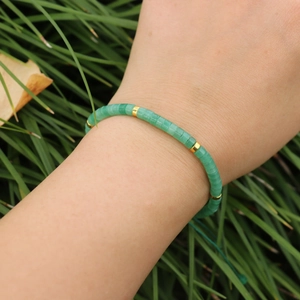 Close-up of imperial stone beaded bracelet with golden spacers and green woven cord