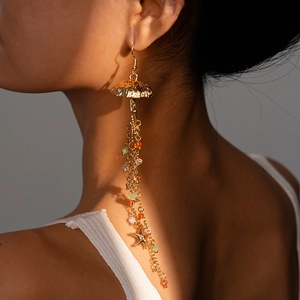 Detailed shot of long gold tassel earrings with colorful beads and starfish charms