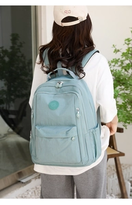 Rear view of a model wearing the turquoise nylon backpack with multiple compartments