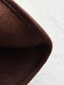 Detailed close-up showing stitching craft and suede texture on dark brown leather jacket