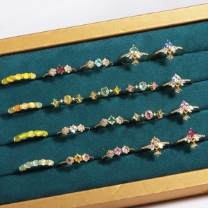 Detailed macro view of colorful gemstone rings on a luxury dark green velvet display tray