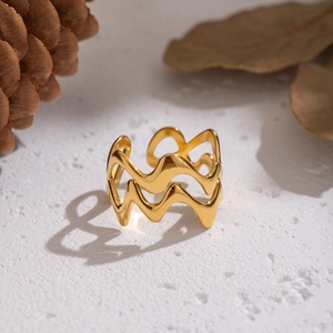 Détail macro d'une bague ouverte dorée ondulée sur une surface blanche texturée