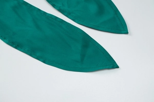 Détail de laçage en satin vert émeraude et coutures soignées sur un ensemble de mode
