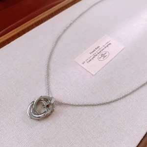 Detail of silver interlocking triple ring pendant on a fine chain over vintage card
