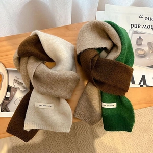 Rainbow knit scarves in earthy tones on a wooden table for warm winter styling
