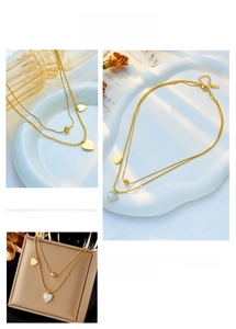 Detail of layered gold heart necklace with white shell pendant on vintage background
