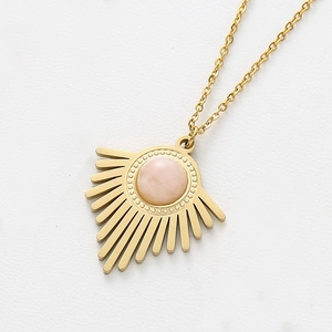 Gros plan détaillé du pendentif rayon de soleil doré avec cristal rose serti