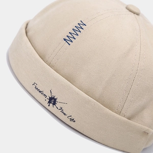 Beige cotton brimless docker hat with blue letter embroidery and freedom graphic