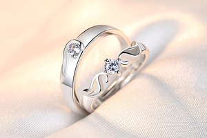 Close-up of couple rings featuring angel wing design and sparkling round zircons on silk