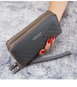 Detail of gray embossed faux leather wallet with double zippers and a wrist strap