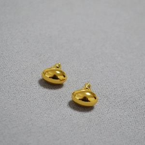 Polished gold oval stud earrings with mirror finish on grey textured background