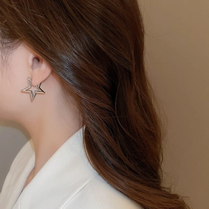 Close-up of model wearing silver hollow star-shaped metal hoop earrings in French style