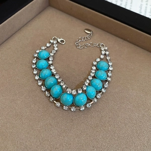Détail du bracelet bohème en turquoise avec strass brillants sur velours beige