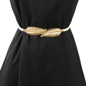 Detail of gold leaf metal waist chain on a black dress showing leaf vein texture