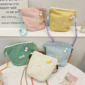 Detailed view of colorful knitted mini phone bags with pom-pom charms and rope straps