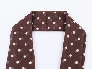 Dettaglio di una sciarpa leggera in chiffon marrone a pois bianchi e della trama