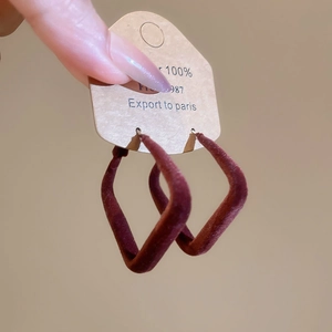 Gros plan sur des boucles d'oreilles géométriques en velours rouge vin élégantes