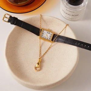 Dettaglio della collana con ciondolo mano dell'amicizia e orologio vintage retrò