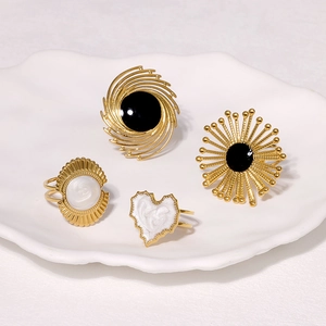 Flat lay of four gold stainless steel rings with black and white enamel flower heart patterns