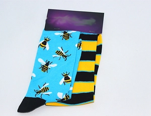 Detail of blue cotton bee pattern socks and yellow striped socks with black packaging tag
