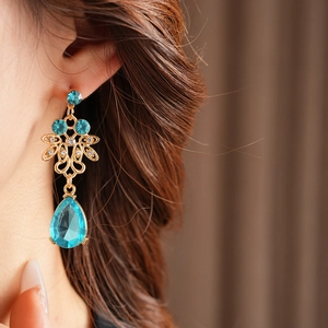 Close-up of vintage golden hollow earrings with blue zircon drop tassels on a model