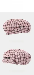 Detail of pink plaid beret featuring a black bow accent and lightweight cotton fabric