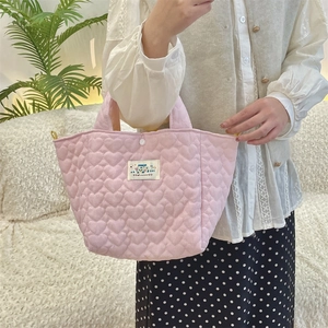 Close-up of pink quilted fabric with heart patterns and Happy label on portable handbag