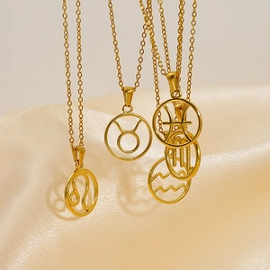 Golden titanium steel zodiac necklaces hanging on soft beige silk with a metallic luster