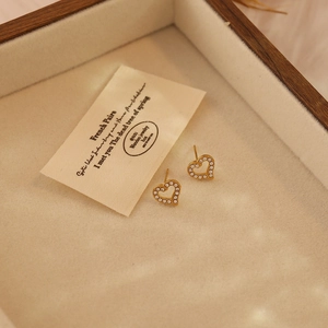 Minimalist gold heart-shaped stud earrings with crystals in a wooden jewelry box